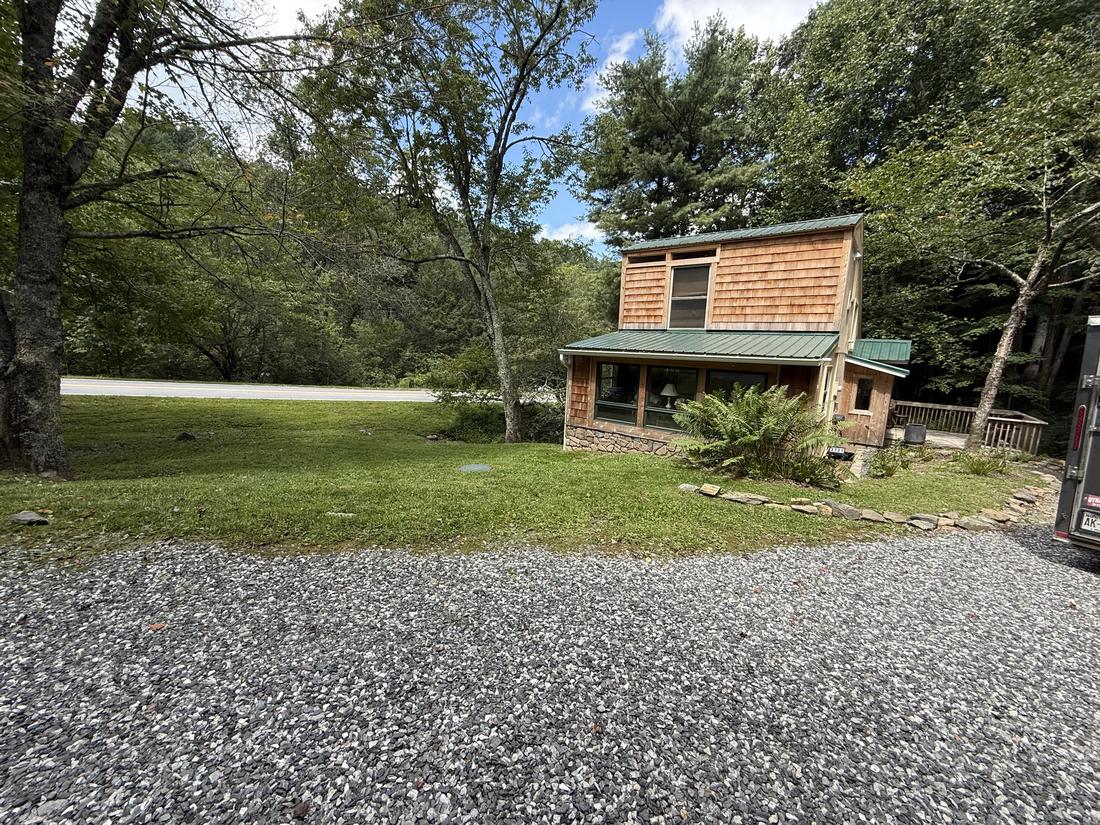 Freshly mowed lawn around a cedar-shingle cabin beside a gravel drive